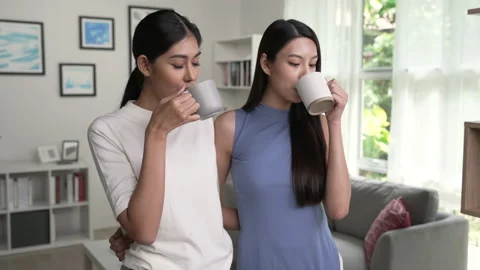 Young Asian Lesbian couple drinking coffee together at home. Видео 213459043