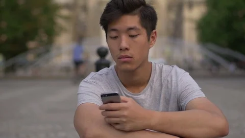 Young Asian Man browsing his phone Stock Footage 77806477