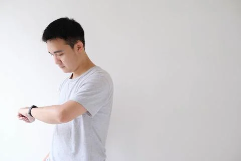 A young Asian man is checking the clock on a smartwatch on his left wrist Stock Photos