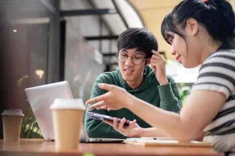 A young Asian man is confusing with something while her friend is explaining. Stock Photos