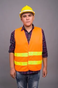 Young Asian man construction worker against gray background Foto stock
