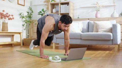 Young asian man doing home workout while watching online tutorial on laptop.. Stock Footage 308310115