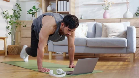 Young asian man doing home workout while watching online tutorial on laptop.. Stock Footage 308311978