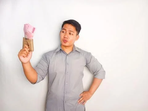 Young Asian man doing thinking gesture while holding Indonesia paper money Stock Photos