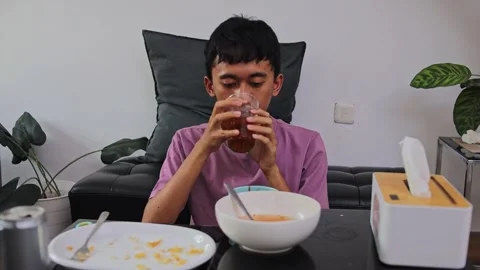 Young Asian man drinking iced tea and wiping mouth with tissue paper after Stock Footage 346032655