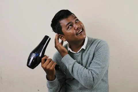 A young asian man is drying his hair with a hairdryer Stock Photos