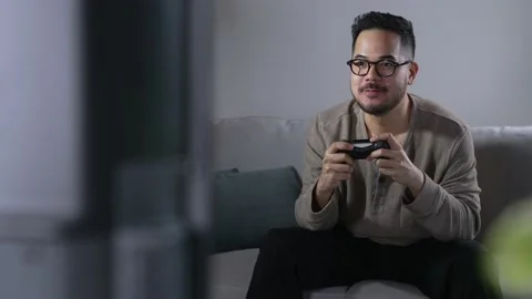 Young Asian man engaging and playing video game with concentrated expression Video stock 167940997