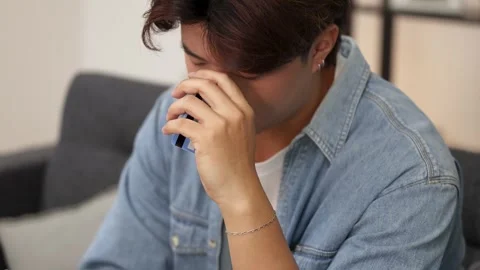 Young Asian Man Feeling Stressed While Using Smartphone and Credit Card Stock Footage 331561731