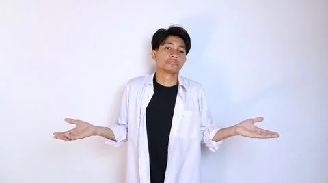 Young asian man gesturing not knowing how, confused by stretching out his t.. 写真素材