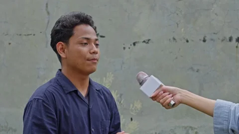 Young Asian man giving interview to off-screen reporter gesturing while speaking Stock Footage 335017713