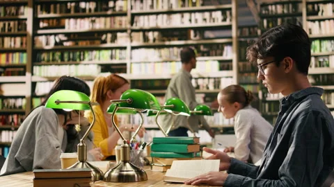 Young asian man with glasses reading book at library study table Stock Footage 336359002