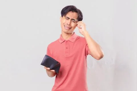Young Asian man holding empty wallet with funny frustrated expression Stock Photos