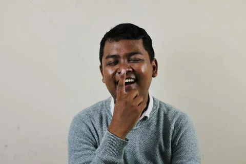 A young asian man is laughing while holding his nose Stock Photos