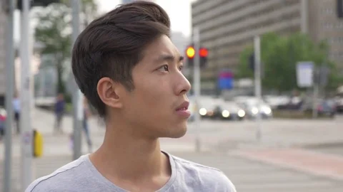 Young Asian Man looking around the intersection in a city Stock Footage 77805585