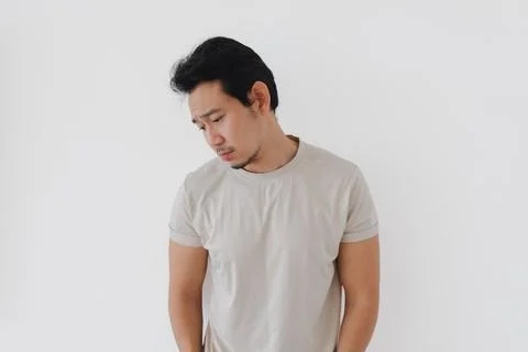 Young Asian Man Looking Down with a Pensive Expression Fotos Stock