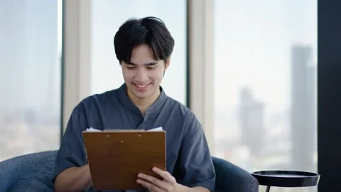 Young asian man is looking at the files his team submitted, feeling happy Stock Footage 293474107