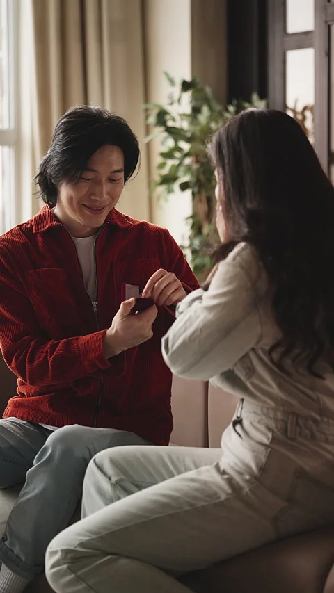 Young Asian man making proposal to his woman at home, presenting engagement ring Stock Footage 330404781