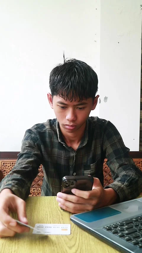 Young Asian man multitasking with laptop, smartphone, and credit card Stock Footage 324950498