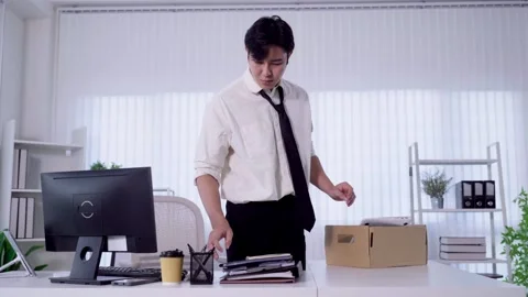 Young Asian man packing personal belongings into box while resigning from o.. Stock Footage 345197580