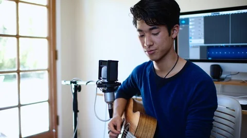 Young Asian Man Performs Song with Guitar in His Home Recording Studio Stock Footage 112637498