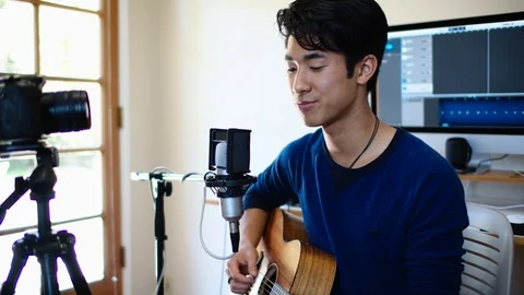 Young Asian Man Performs Song for Social Media Fans in His Home Recording Studio Stock Footage 112638299