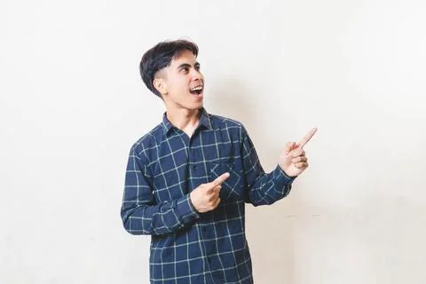 Young Asian man pointing to the side with an excited expression, highlighti.. Stock Photos