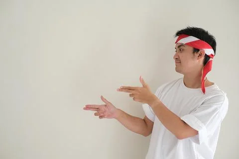 A young Asian man points to the left side in Hari Kemerdekaan Indonesia or .. Stock Photos