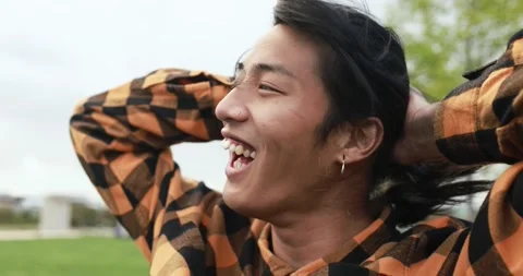 Young asian man posing in front of camera at city park Stock Footage 192384417