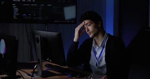 Young Asian man reviews computer monitors while touching temple and face Stockbeeldmateriaal 343733047