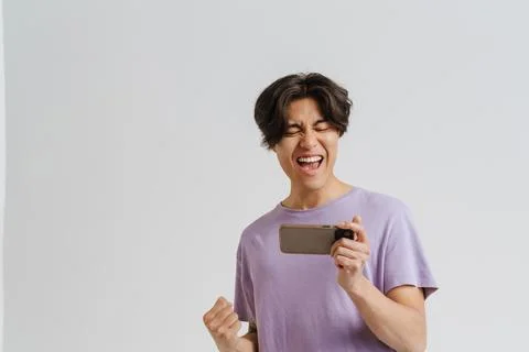Young asian man screaming while playing game on cellphone Foto stock