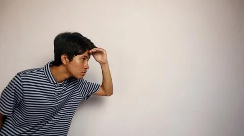 A young Asian man is on the side posing and looking at something on the oth.. 写真素材