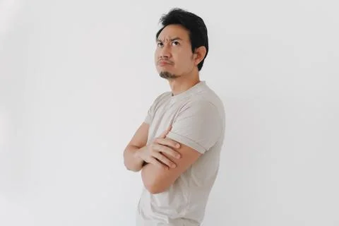 Young Asian man with skeptical expression, arms crossed, looking up in thou.. Stock Photos