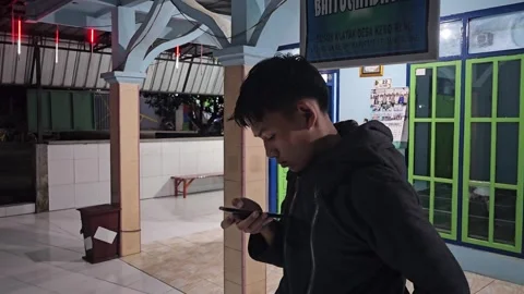 Young Asian Man Standing On Mosque Porch Using Smartphone At Night Stock Footage 339829704
