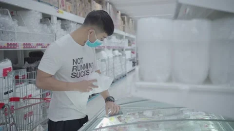 A young asian man taking packs of frozen food at supermarket's freezer Stock Footage 136750406