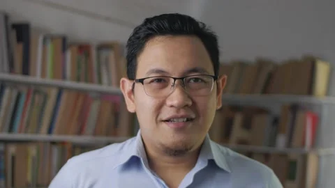Young Asian man talking to camera while standing inside library, businessman  Stock Footage 146765702