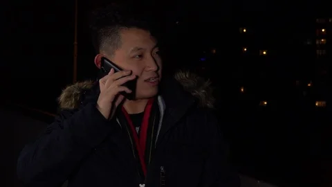 A young asian man talks on a smartphone in an urban area at night Stock-Footage 87976368