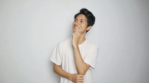 Young Asian man thinking while looking up and hand holding chin 写真素材