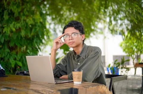 Young Asian man thinking while looking to his laptop. Stock Photos
