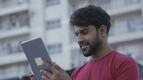 Young Asian man using digital tablet while standing in balcony of home. Asian Stock-Footage 154036448