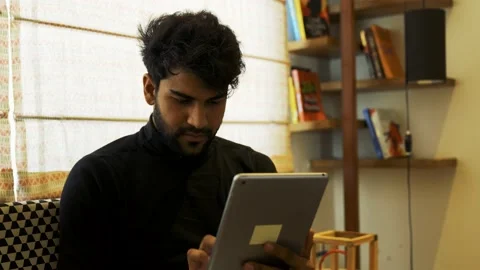 Young Asian man using digital tablet while sitting on couch at home. Video stock 155197078