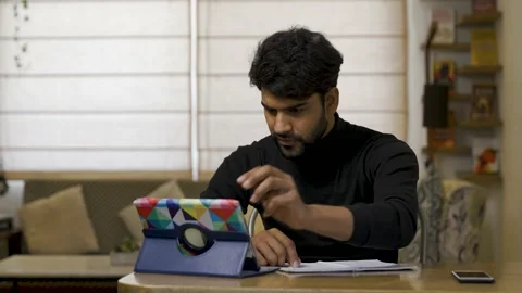 Young Asian man using digital tablet while sitting on table at home. Stock Footage 155200686