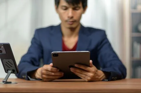 Young Asian Man Using Digital Tablet at Workspace in Modern Office Environmen Stock Photos
