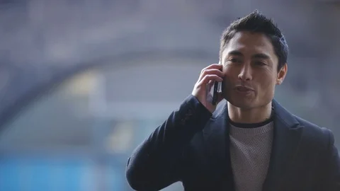 Young asian man using his cellphone and answering a call Stock Footage 85399434
