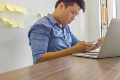 Young Asian man using phone in office Stock Photos