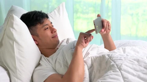 Young Asian man using a smartphone in his bed Video stock 156639019