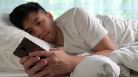 Young Asian man using a smartphone in his bed Stock-Footage 156639209