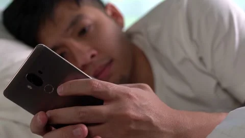 Young Asian man using a smartphone in his bed Видео 156639215