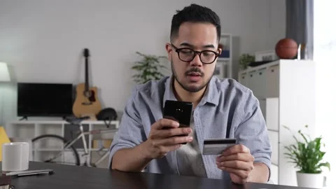 Young Asian man using smartphone holding credit card for online shopping Stock Footage 167940672