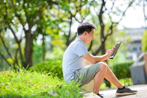 Young asian man using tablet in park Stock Photos