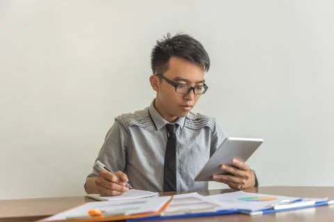 Young Asian man using tablet and writing Stock Photos